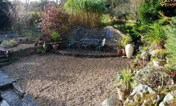 A garden depicting Spain, with a patio featuring mosaics, large pots, a pebble beach and spiky plantings